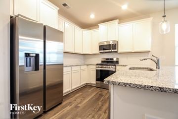 Greenville house for rent - a kitchen with white cabinets and stainless steel refrigerator