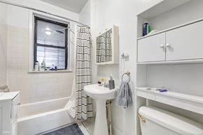 Chicago apartment for rent - A white bathroom with a tub, sink, and toilet.