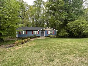 Greenville house for rent - A blue house with red trim is surrounded by green trees.