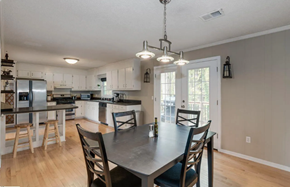 Greenville house for rent - A kitchen with a table and chairs in the foreground and a refrigerator, oven, and cabinets in the background.