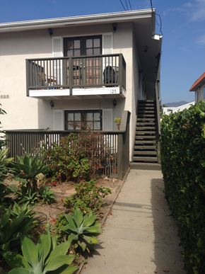 Carpinteria apartment for rent - A white two-story building with a balcony and stairs leading up to it.