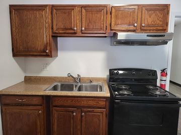 Coatesville apartment for rent - A kitchen with a black stove and wooden cabinets.