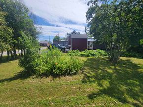 Westville apartment for rent - A red building is surrounded by greenery and a car is parked in the driveway.