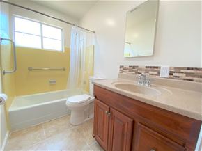 Merced house for rent - A bathroom with a yellow wall and a white bathtub.