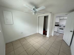 Fort Myers apartment for rent - A room with a ceiling fan and a doorway leading to a kitchen.