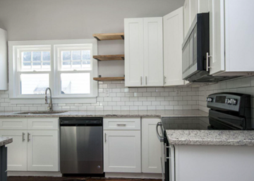 Greenville house for rent - A kitchen with white cabinets and a black dishwasher.