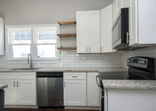 Greenville house for rent - A kitchen with white cabinets and a black dishwasher.