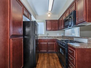 Indio apartment for rent - a kitchen with wooden cabinets and a black refrigerator