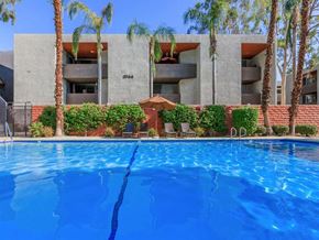 Palm Springs apartment for rent - a large swimming pool in front of a building with palm trees