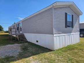 Shawnee house for rent - A mobile home with a deck and a car parked in the background.