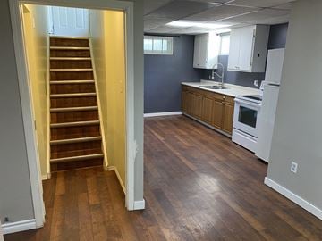 Prince Albert house for rent - a view of a kitchen and stairs from the living room with a stove and sink