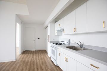 Bronx apartment for rent - A kitchen with white cabinets and a stove top oven.