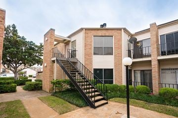 Houston apartment for rent - A brick house with a black staircase leading to the second floor.