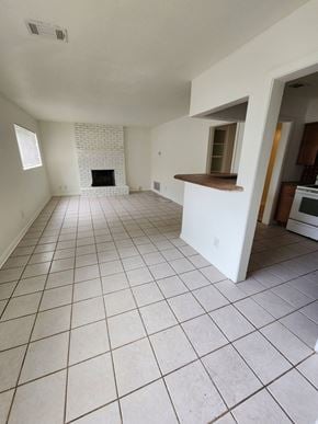 Pensacola house for rent - an empty living room with a tiled floor and a fireplace