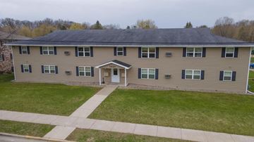Shawano apartment for rent - a large tan house with a sidewalk in front of it