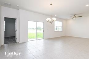 Kissimmee house for rent - A spacious room with a sliding glass door leading to a balcony, a ceiling fan, and a chandelier.