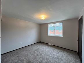 Clairton house for rent - A room with a window showing a red building outside.