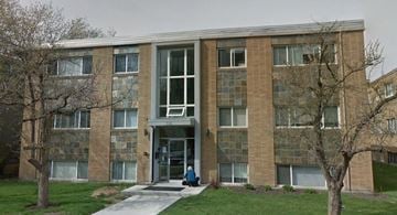 Calgary house for rent - a woman sitting in front of a brick building