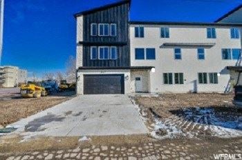 Midvale house for rent - A modern two-story building with a garage door and a construction vehicle in front.