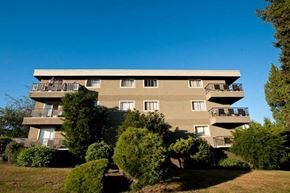 New Westminster apartment for rent - A large building with balconies is surrounded by greenery.