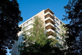 Vancouver apartment for rent - A tall building with balconies is surrounded by trees.