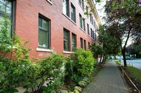 Vancouver apartment for rent - A red brick building with green bushes in front.