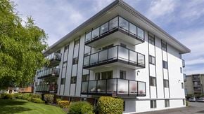 Victoria apartment for rent - A white apartment building with black balconies and windows.