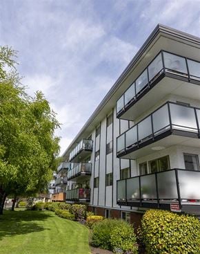 Victoria apartment for rent - A modern building with balconies and a green lawn in front.