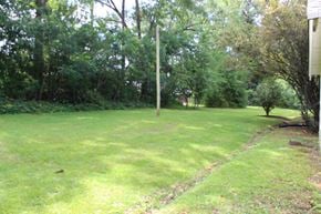 Hattiesburg house for rent - a grassy yard with trees and a house