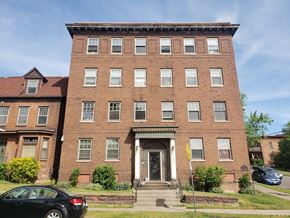 Duluth apartment for rent - A black car is parked in front of a red brick building.