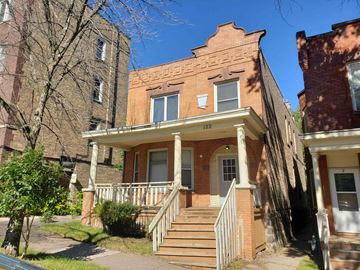 Duluth apartment for rent - A red brick house with a porch and a tree in front.