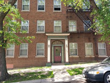 Duluth apartment for rent - A brick building with a red door and a tree in front.