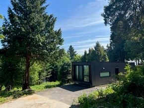 Vancouver apartment for rent - A modern house is surrounded by trees and greenery.