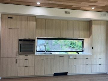 Vancouver apartment for rent - A kitchen with wooden cabinets and a television mounted above the counter.