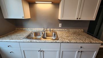 Cincinnati apartment for rent - a kitchen with white cabinets and granite counter tops and a sink