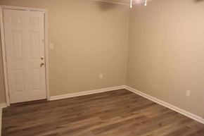 Petal apartment for rent - an empty room with wooden floors and a white door