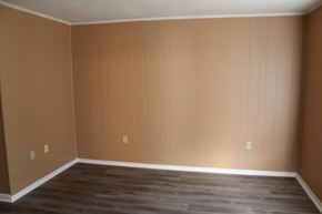 Petal apartment for rent - an empty living room with brown walls and a wooden floor