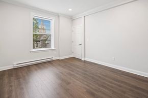 Summit apartment for rent - A room with a wooden floor and a window showing a building outside.