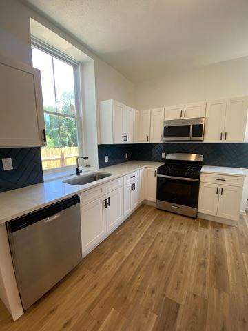 Louisville apartment for rent - A kitchen with wooden floors and white cabinets.