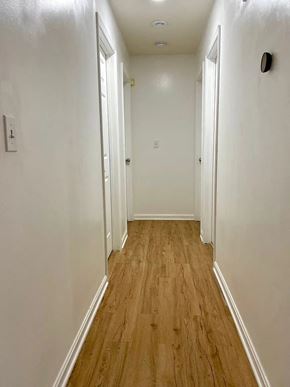 Louisville house for rent - a hallway with wood floors and white walls