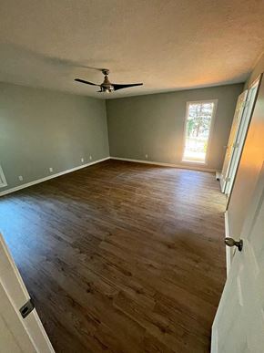 Louisville house for rent - a empty living room with a ceiling fan and wood floors