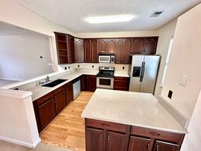 Greer house for rent - A kitchen with brown cabinets and a white countertop.