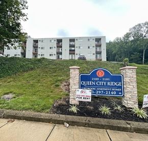 Cincinnati apartment for rent - A sign for Queen City Ridge 1 Bedroom Apartment Homes is in front of a building.