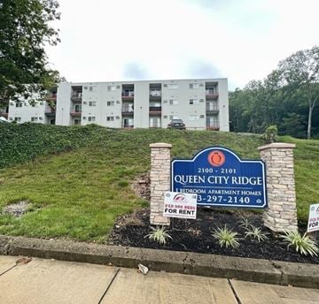 Cincinnati apartment for rent - A sign for Queen City Ridge 1 Bedroom Apartment Homes is in front of a building.