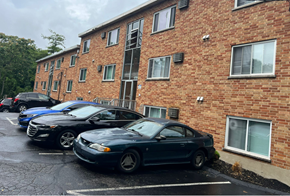 Cincinnati apartment for rent - A black car is parked in a parking lot in front of a brick building.