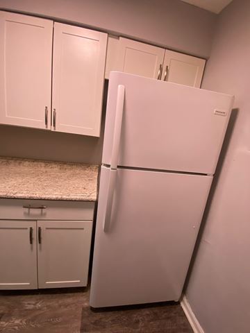 Cincinnati apartment for rent - A white refrigerator stands in a kitchen next to white cabinets.