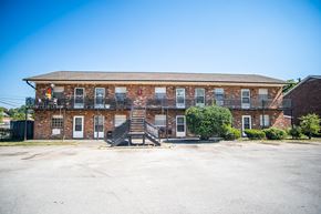 Knoxville apartment for rent - A red brick building with a parking lot in front.