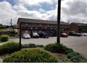 Knoxville apartment for rent - A parking lot with cars and a building in the background.