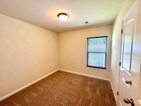 Greenville house for rent - A room with a carpeted floor, a window with blinds, and a white door.