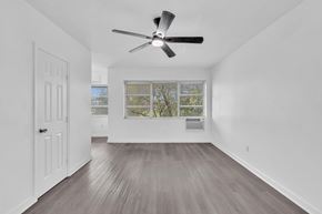 Miami apartment for rent - A room with a ceiling fan and a window with a view of trees.